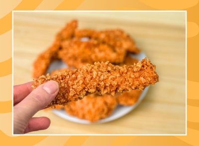 hand holding a chicken tender on an orange background