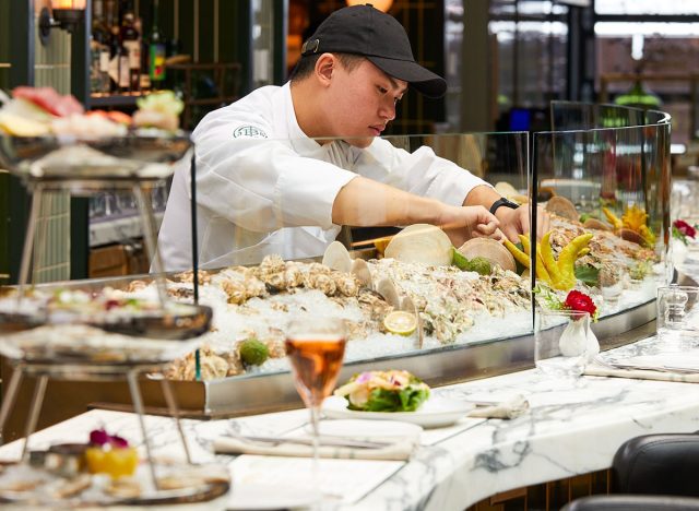 An oyster shucker tends the raw bar at Fulton Fish Co. in the Tin Building by Jean-Georges in NYC