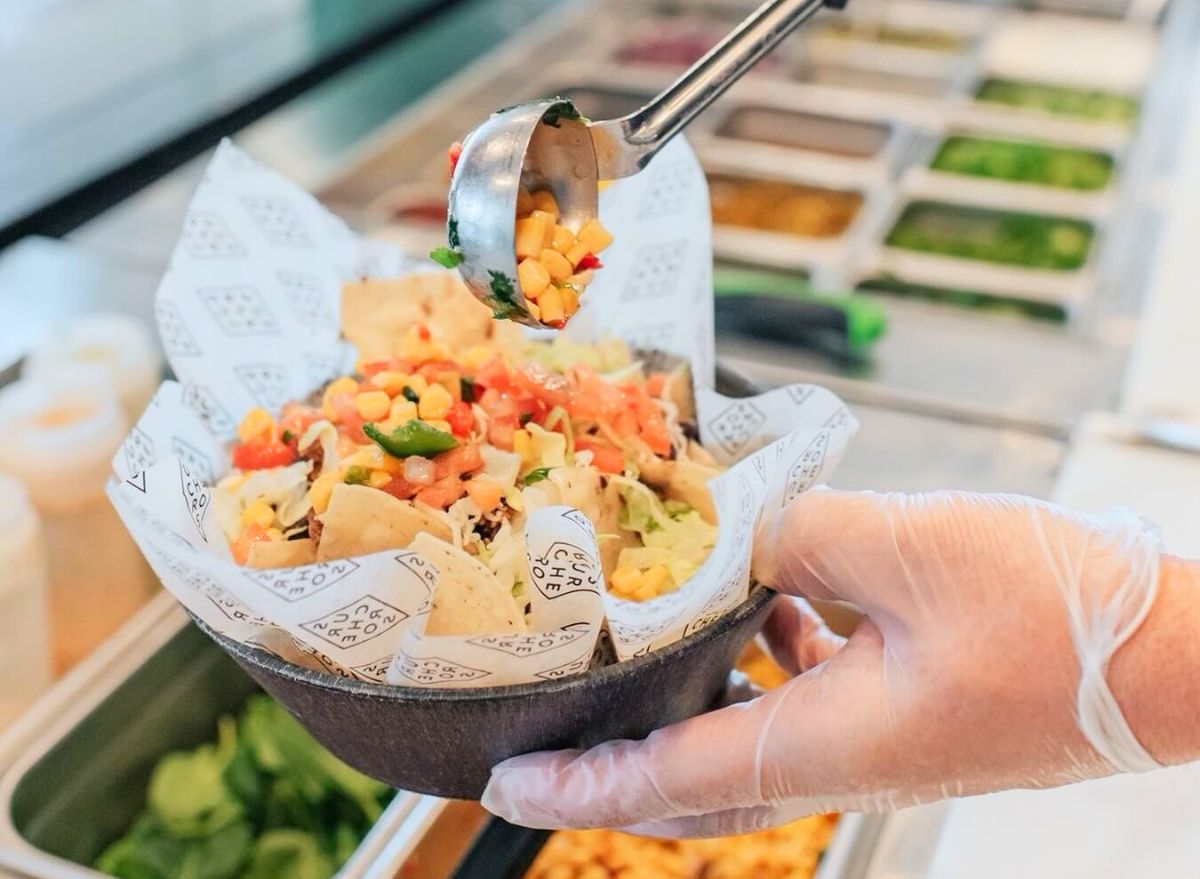 Surcheros worker scooping toppings onto bowl