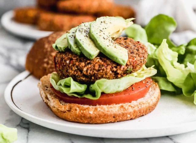 veggie burger on a bun with avocado slices, lettuce, and tomato