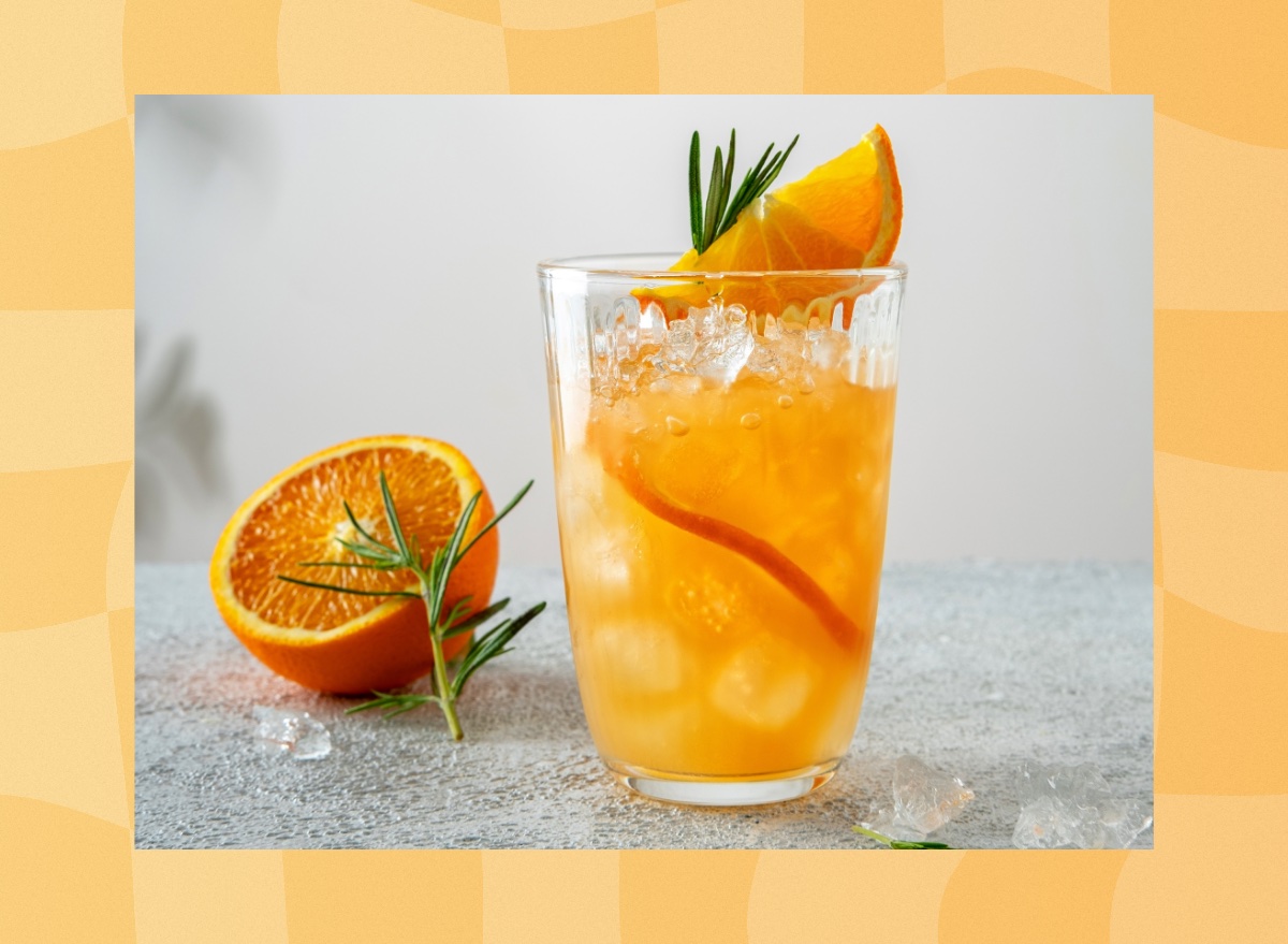 tall glass of orange juice adrenal mocktail with fresh orange slices and rosemary