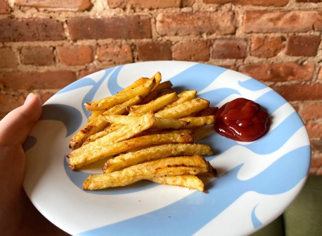 hand holding a plate of fries