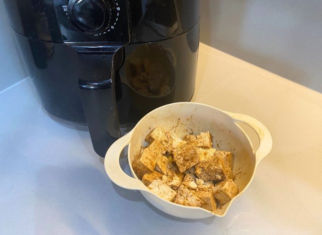 bowl of marinated tofu in front of an air fryer