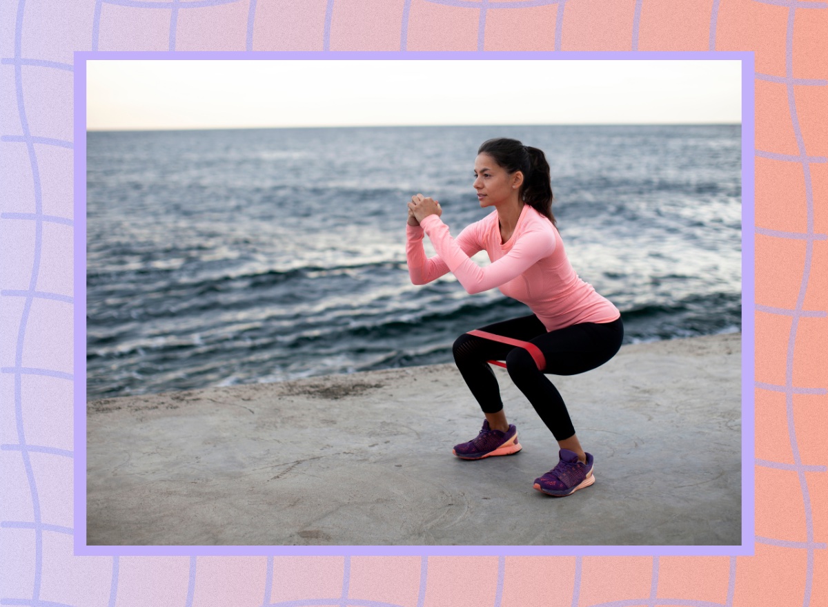 woman doing resistance band squats at the beach