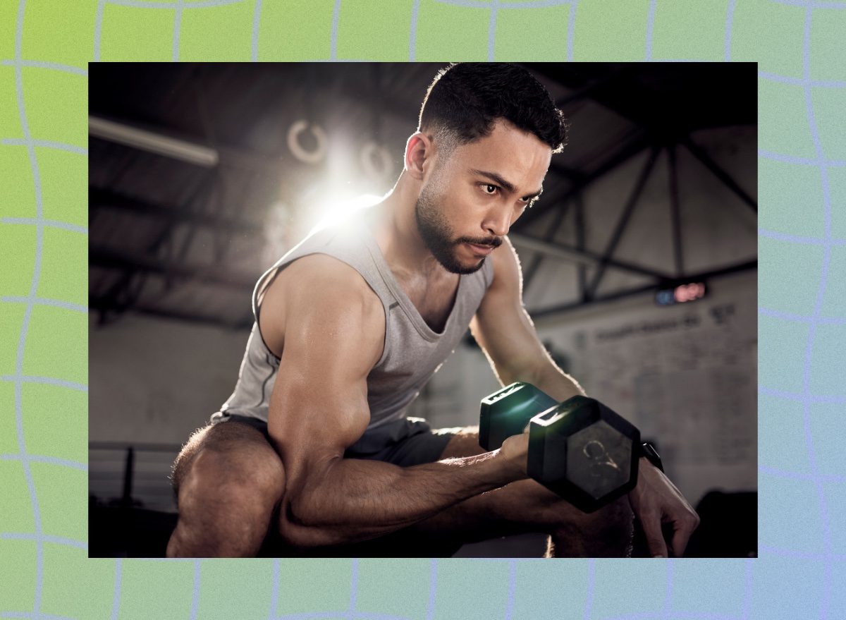 fit, muscular man doing bicep curls in dark gym