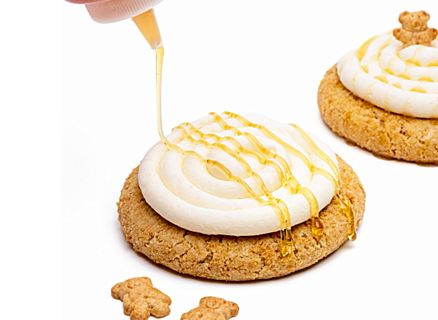 crumbl graham cracker cookies being drizzled with honey on a white background