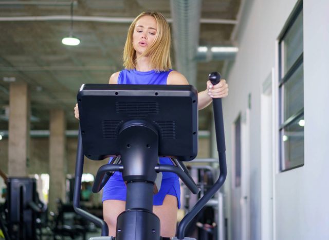 concentrated woman doing intense elliptical workout at the gym