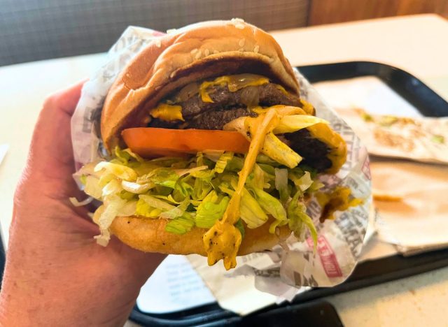 a photo of a hand holding the habit burger grill double char burger