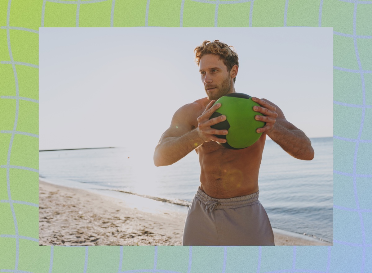 fit, shirtless man doing medicine ball workout on the beach