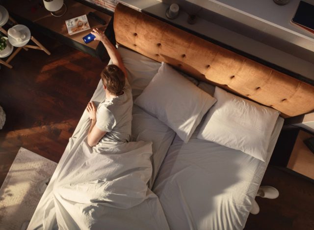 man turning off his alarm in bed