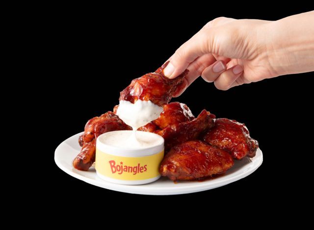 person dipping bojangles chicken wing into ranch