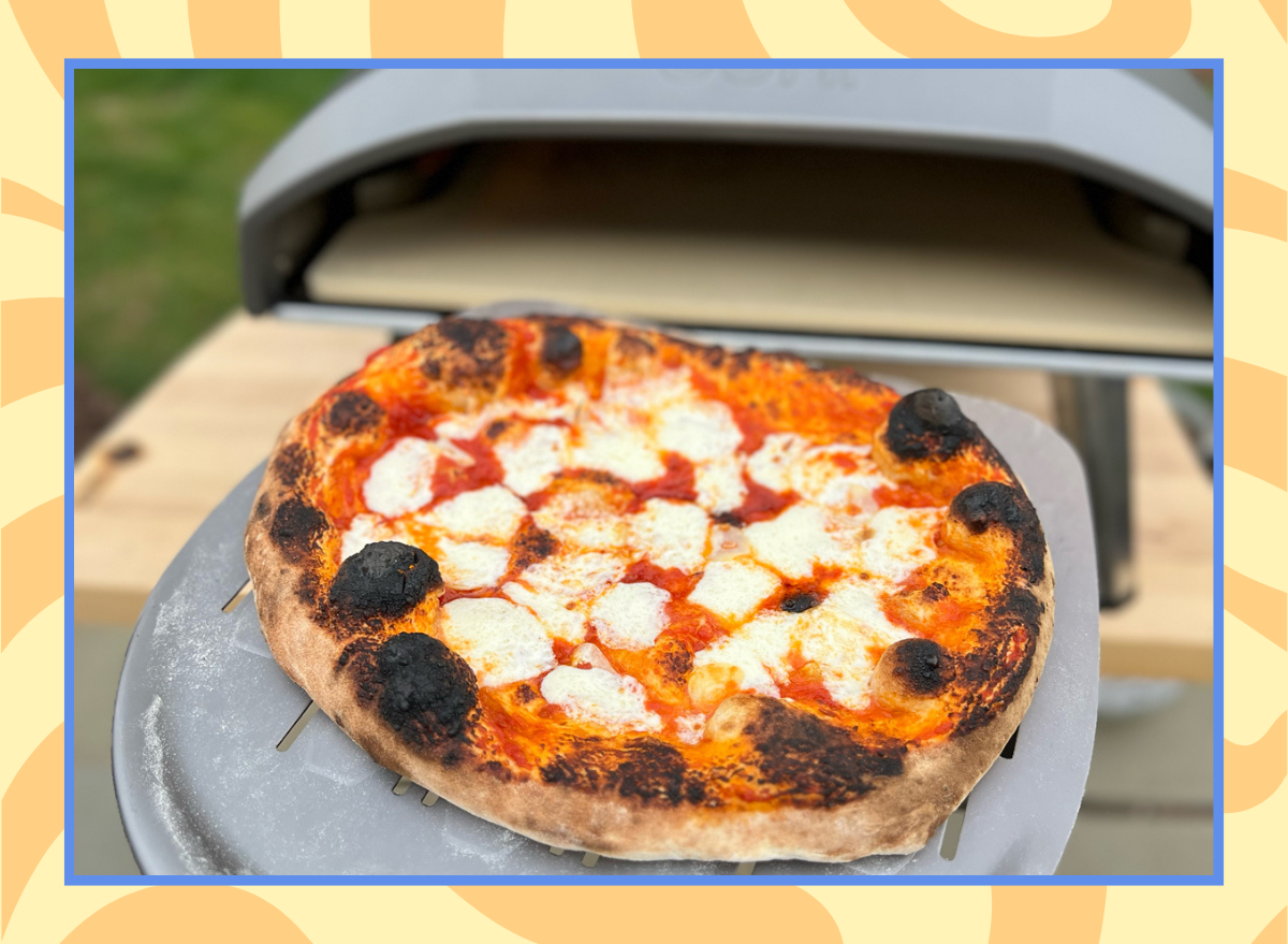 image of pulling a freshly made pizza out of the ooni koda oven on a yellow background