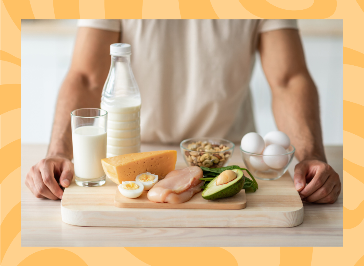 man standing behind a wooden board full of high protein foods