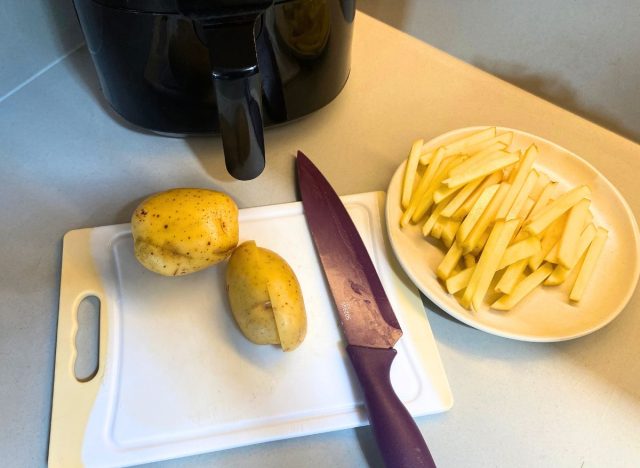 potatoes and a knife next to a plate of sliced potatoes