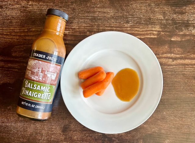 trader joe's balsamic vinaigrette dressing on a plate with baby carrots next to the bottle of dressing