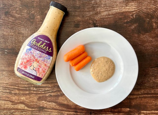 trader joe's godess dressing on a plate with baby carrots next to the bottle of dressing