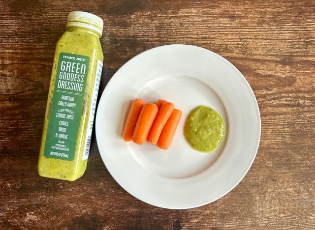 trader joe's green goddess dressing on a plate with baby carrots next to the bottle of dressing