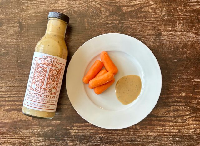 trader joe's organic toasted sesame dressing on a plate with baby carrots next to the bottle of dressing