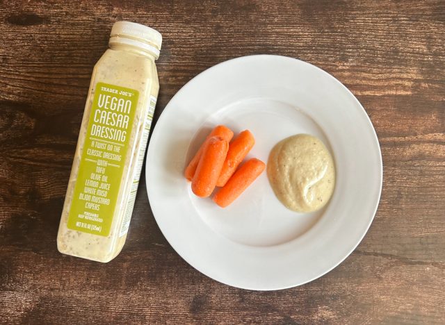 trader joe's vegan caesar dressing on a plate with baby carrots next to the bottle of dressing