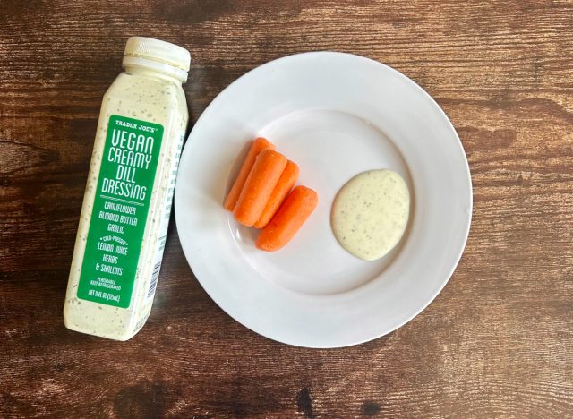 trader joe's vegan creamy dill dressing on a plate with baby carrots next to the bottle of dressing