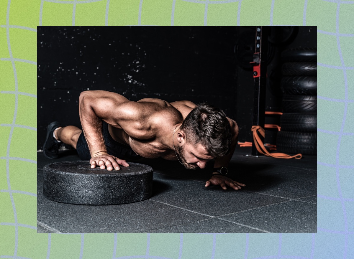 fit, muscular man doing weight plate pushups in dark gym