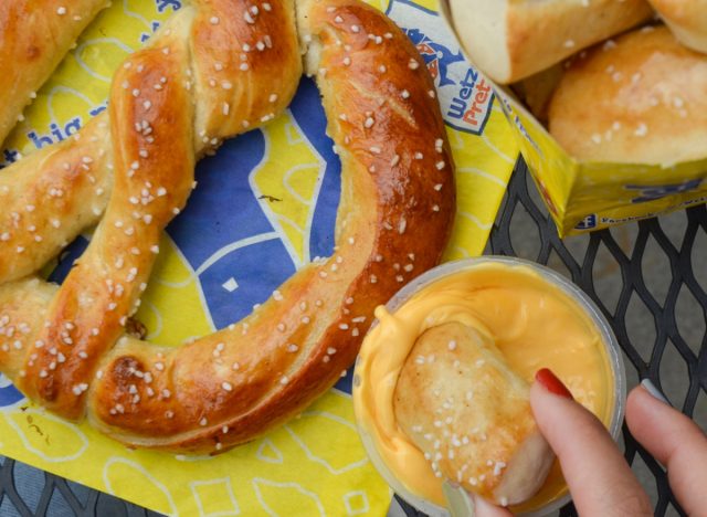 person dipping wetzel's pretzels pretzel bite into cheese