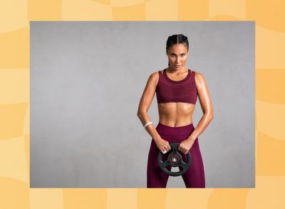 fit woman holding weight plate in front of gray backdrop