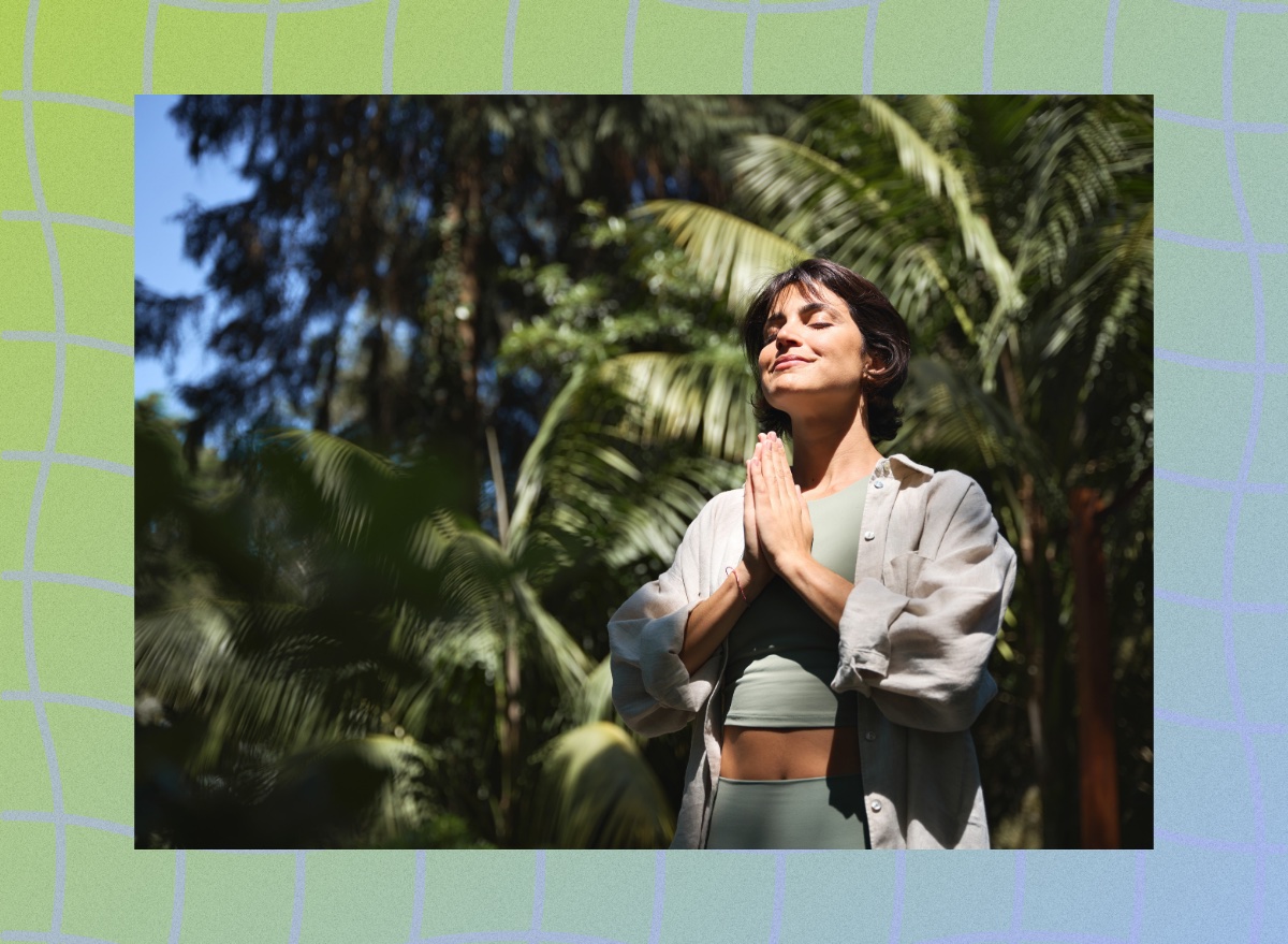 fit brunette woman meditating outdoors in the sunlight among lush green vegetation