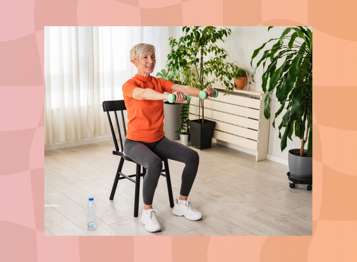 fit, mature woman doing seated ab exercise at home with dumbbells in bright living room