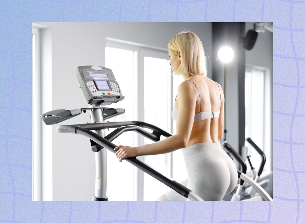 fit blonde woman using the stair climber machine at the gym in front of windows