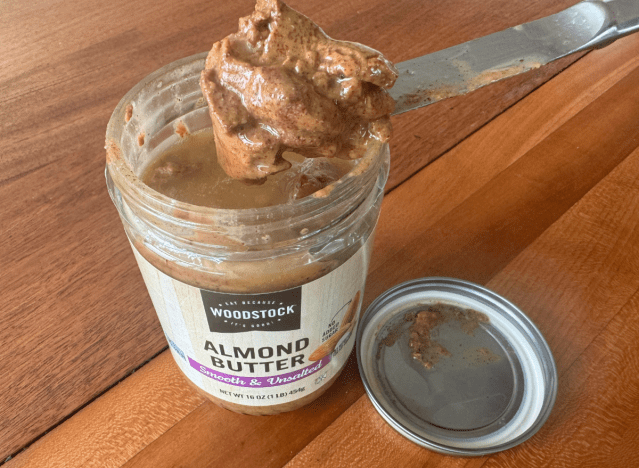 a jar of woodstock almond butter with a knife in it