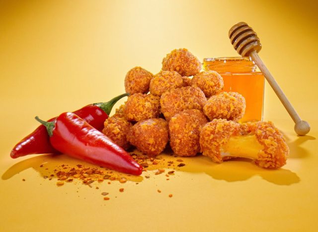 Culver's Hot Honey Cheese Curds, honey, and peppers on yellow background