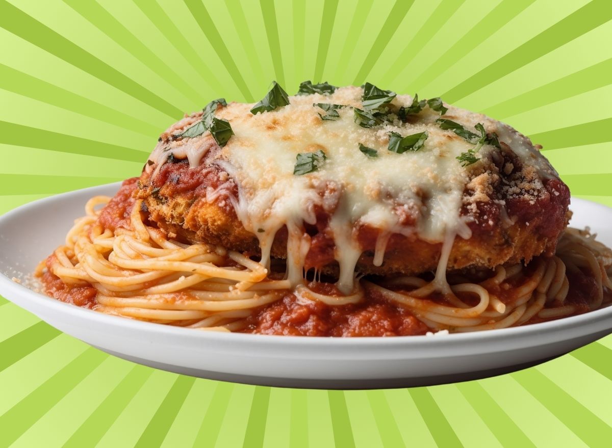 A plate of chicken parmesan over spaghetti set against a colorful background.