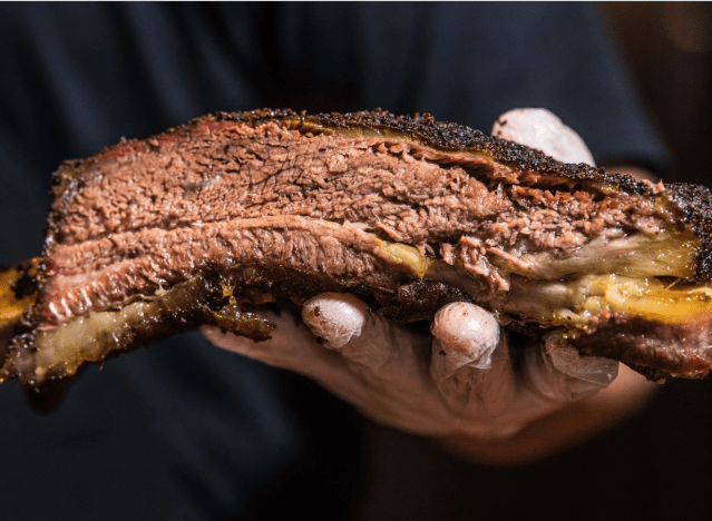 a chef holding a rib from terry black's bbq