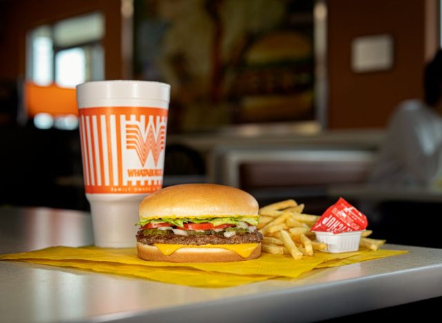 Whataburger burger, fries, drink, and sauce cup on a table