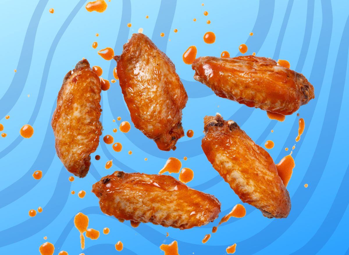 A quintet of saucy Buffalo-style chicken wings set against a vibrant swirly blue background