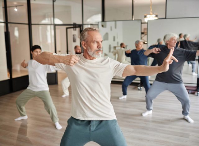 fit, mature man in balancing yoga workout class