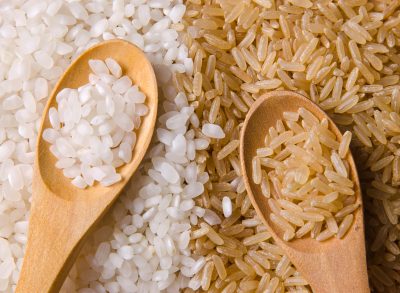 white rice and brown rice with wooden spoons on top