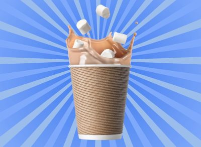 Hot chocolate splashing marshmallows inside a brown paper cup set against a vibrant blue background