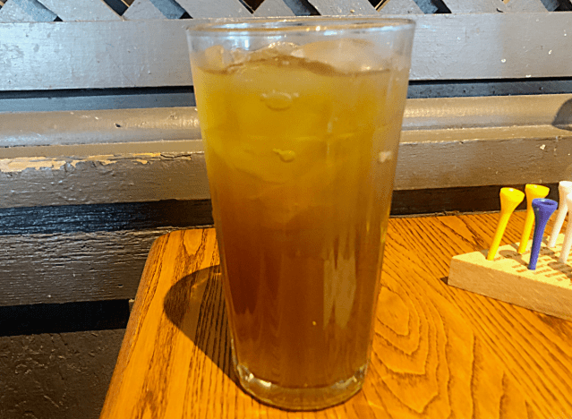 a glass of cracker barrel granny smith ice tea ona table 