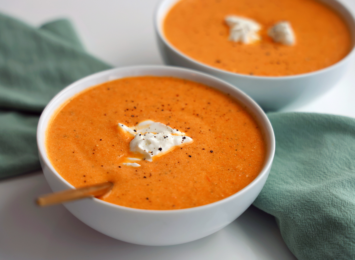 creamy roasted vegetable soup in two bowls on table with napkin