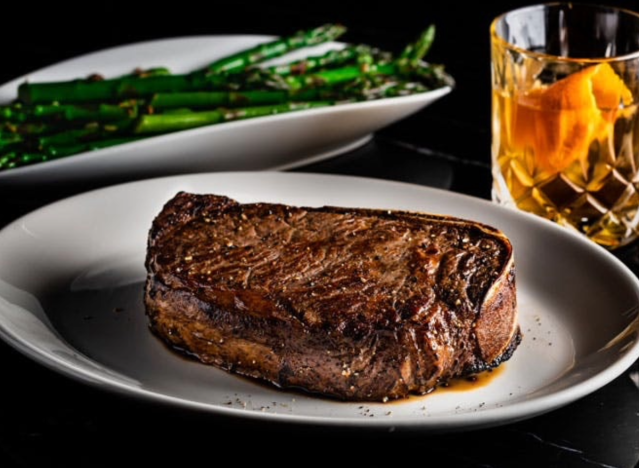 del frisco's prime steak with asparagus and a manhattan