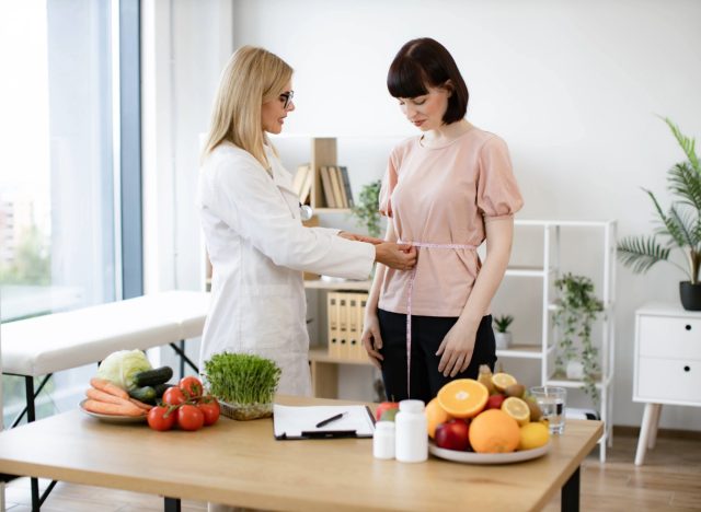 doctor or nutritionist measuring a patient's waist circumference