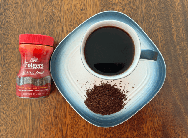 folgers instant coffee can next to a mug of black coffee 