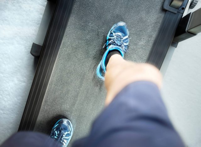 downward view of man looking down while walking on treadmill