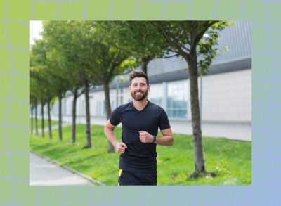 happy man power walking on tree-lined, paved path on sunny day