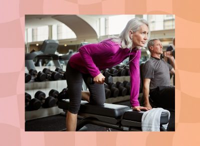 mature, focused woman doing single-arm dumbbell row on workout bench at the gym