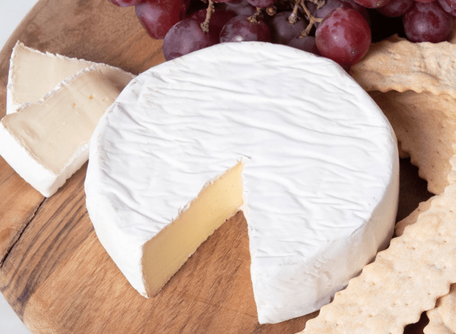 murray's mini brie on a cuting board with crackers and grapes