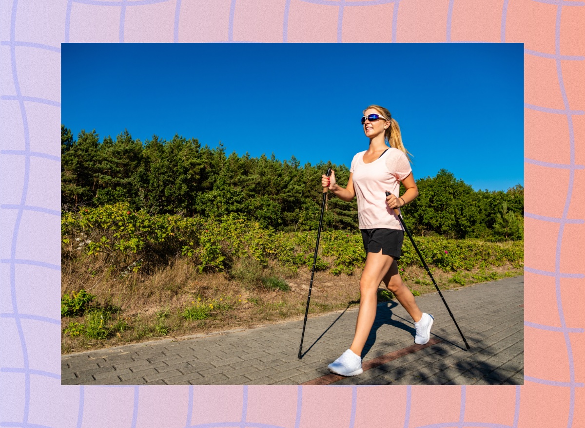 woman Nordic walking along paved path on sunny day