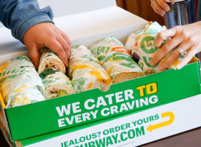 people choosing subway sandwich from catering box